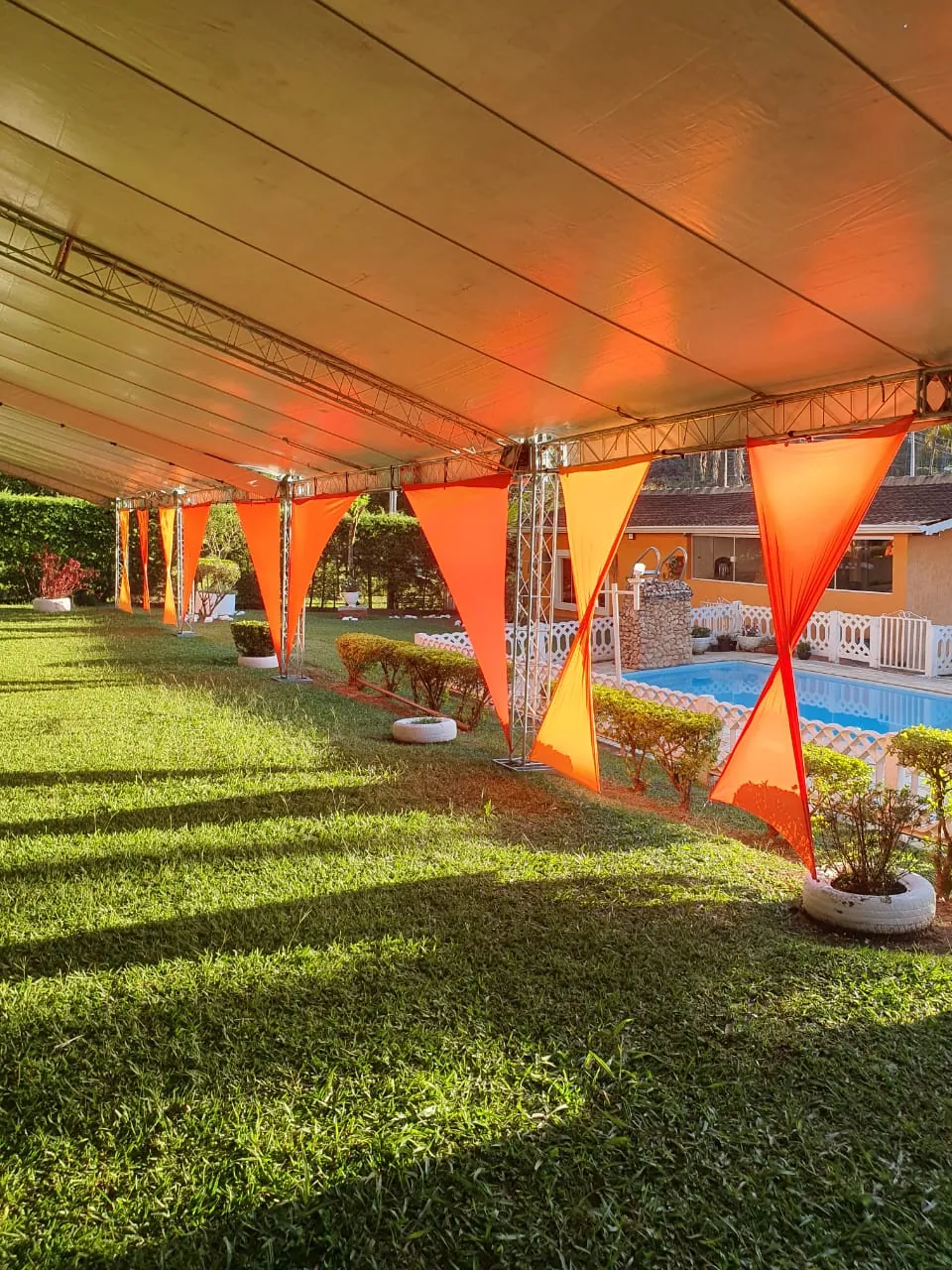 Tenda Box Truss com iluminação laranja ao lado da piscina - Nuestra Fiesta Atibaia